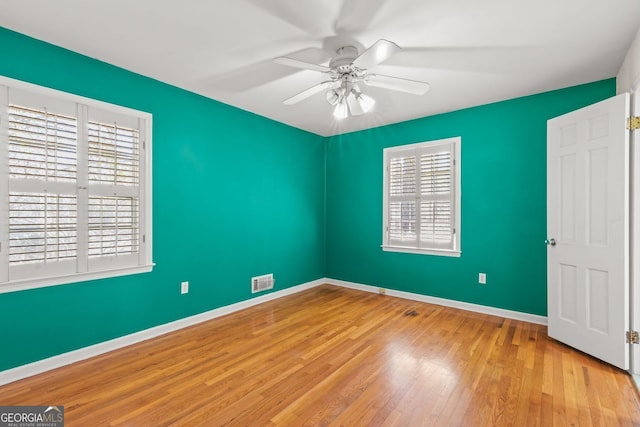 unfurnished bedroom with a ceiling fan, wood finished floors, visible vents, and baseboards