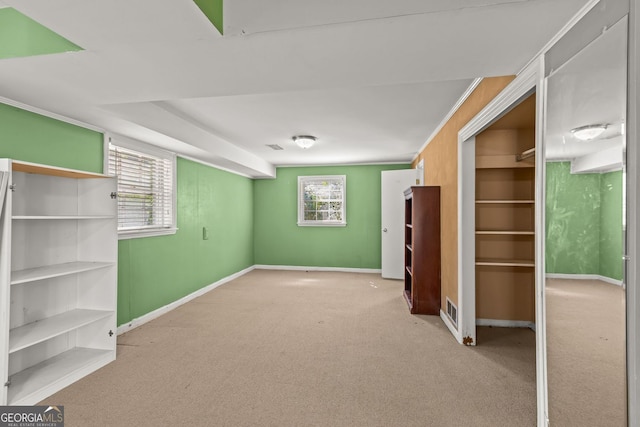 below grade area with carpet flooring, crown molding, visible vents, and baseboards