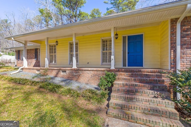 view of exterior entry with covered porch and brick siding