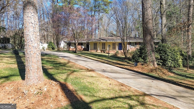 ranch-style house featuring driveway and a front lawn