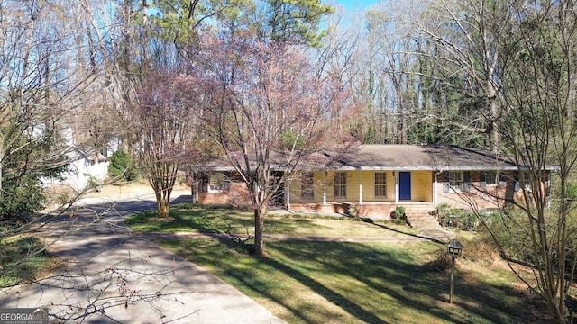 view of front facade featuring a porch, concrete driveway, brick siding, and a front lawn