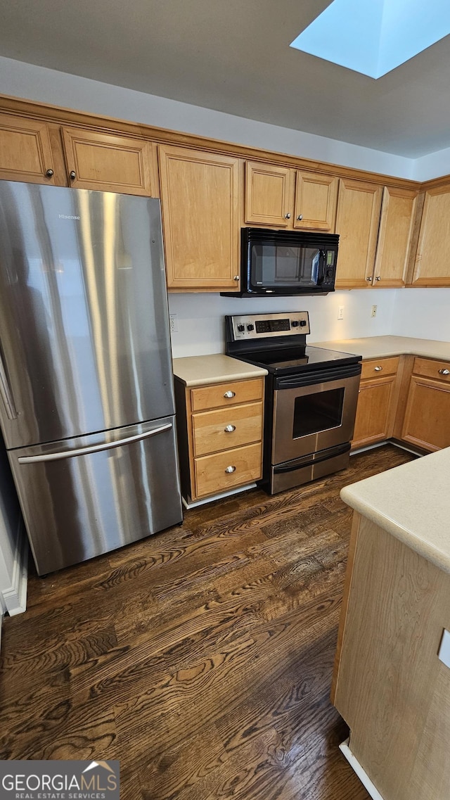 kitchen with light countertops, appliances with stainless steel finishes, dark wood-type flooring, and a skylight