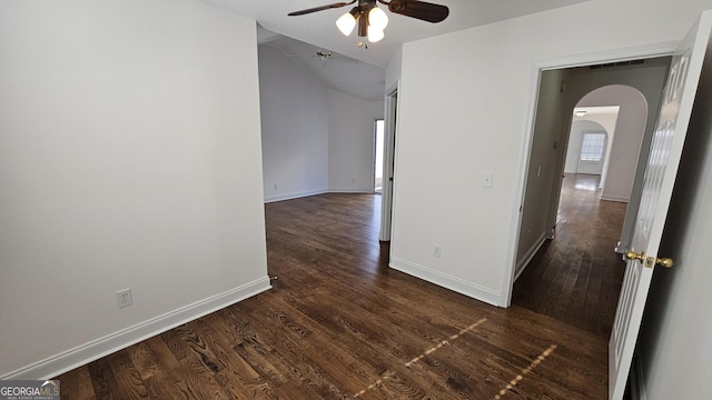 unfurnished room featuring dark wood-style floors, arched walkways, vaulted ceiling, ceiling fan, and baseboards