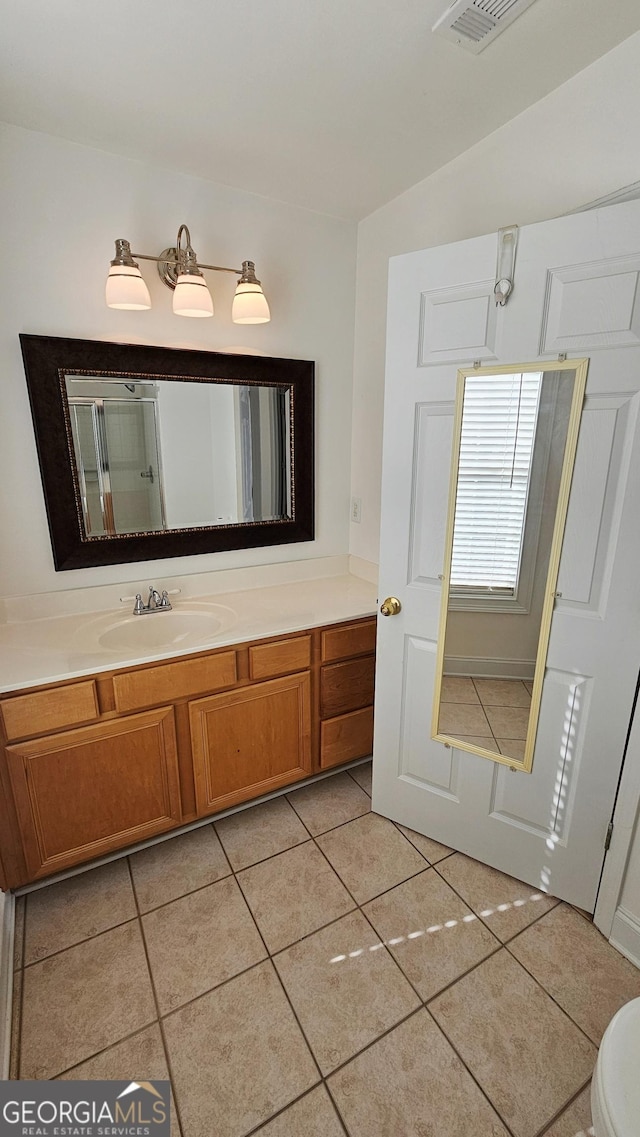 full bath with a shower with door, tile patterned flooring, visible vents, and vanity