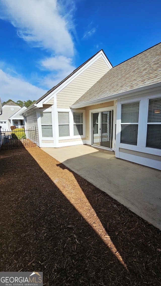 back of property featuring a patio area, roof with shingles, and fence