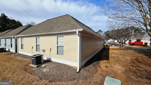 view of side of property featuring cooling unit and roof with shingles