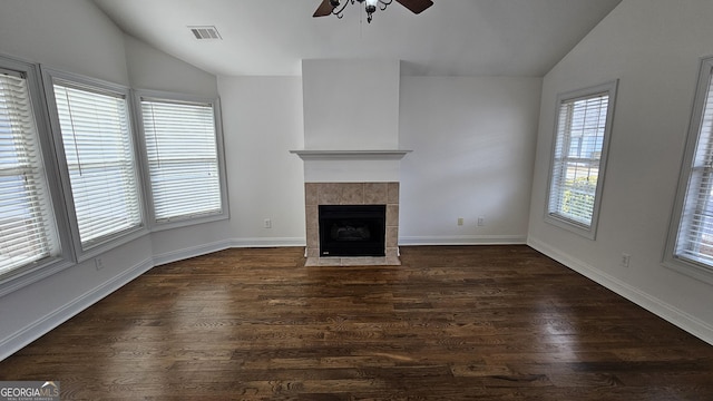 unfurnished living room with vaulted ceiling, dark wood-type flooring, a tile fireplace, and visible vents