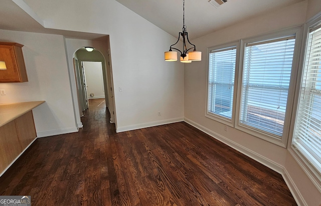 unfurnished dining area featuring arched walkways, visible vents, dark wood-type flooring, vaulted ceiling, and baseboards