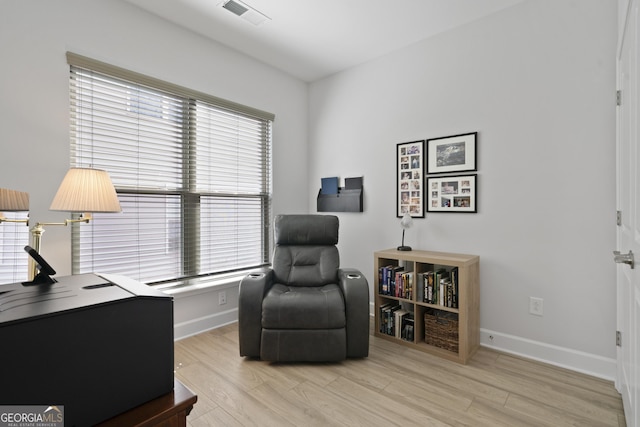 living area featuring baseboards, visible vents, and light wood-style floors