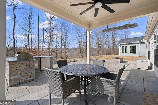 view of patio featuring outdoor dining area, an outdoor kitchen, an outdoor fire pit, a grill, and ceiling fan