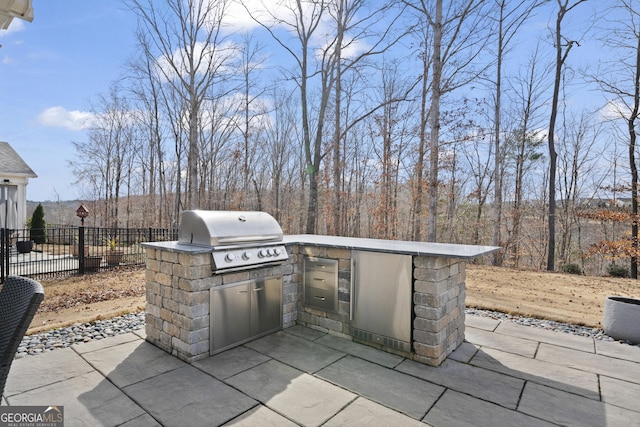 view of patio with exterior kitchen, a grill, and fence