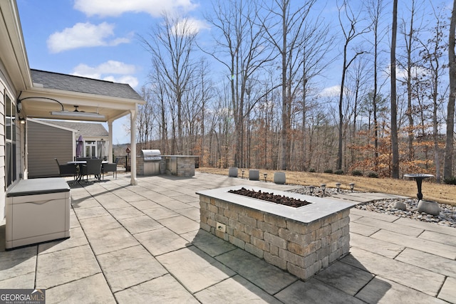 view of patio / terrace featuring an outdoor fire pit, ceiling fan, a grill, exterior kitchen, and outdoor dining space