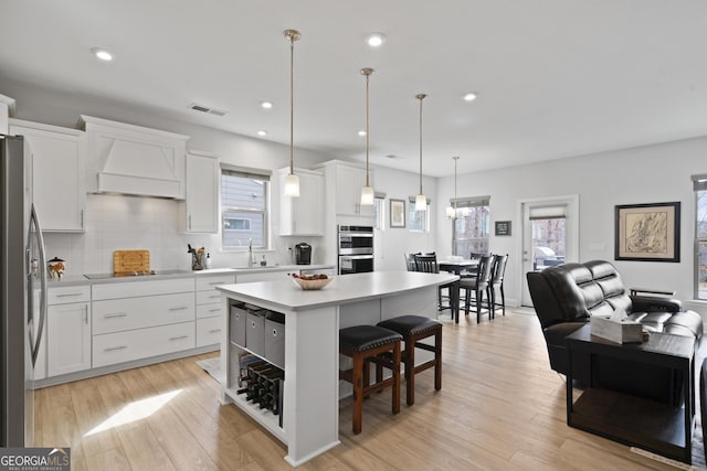 kitchen featuring visible vents, appliances with stainless steel finishes, a kitchen breakfast bar, custom exhaust hood, and a sink