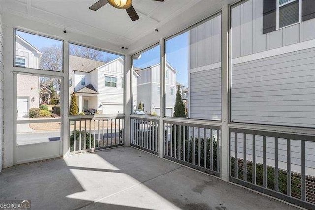 unfurnished sunroom with a residential view, a healthy amount of sunlight, and ceiling fan