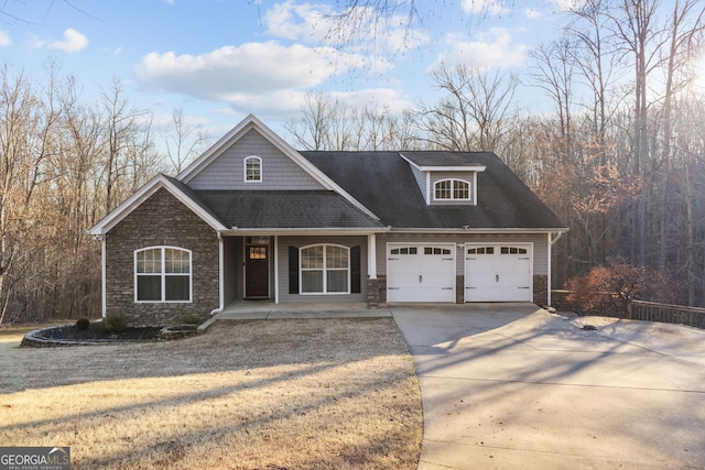 view of front of property with stone siding, covered porch, a shingled roof, and concrete driveway