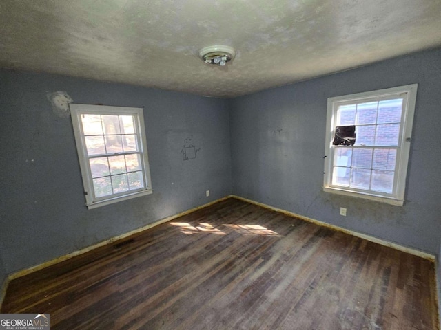 unfurnished room with baseboards, a wealth of natural light, and wood finished floors