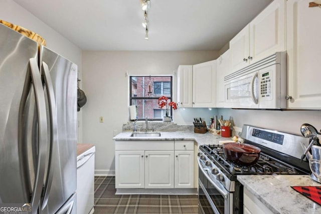 kitchen with light stone countertops, white cabinetry, appliances with stainless steel finishes, and a sink