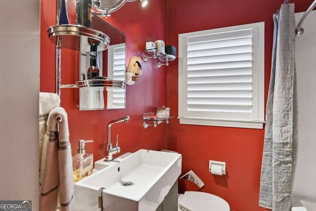 full bath with curtained shower, a sink, and toilet