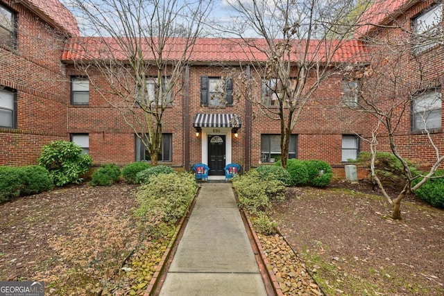 view of front of house featuring brick siding and a tiled roof