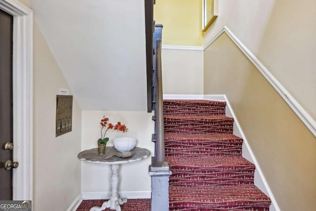 staircase with vaulted ceiling and baseboards