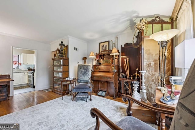 sitting room featuring ornamental molding, wood finished floors, visible vents, and baseboards