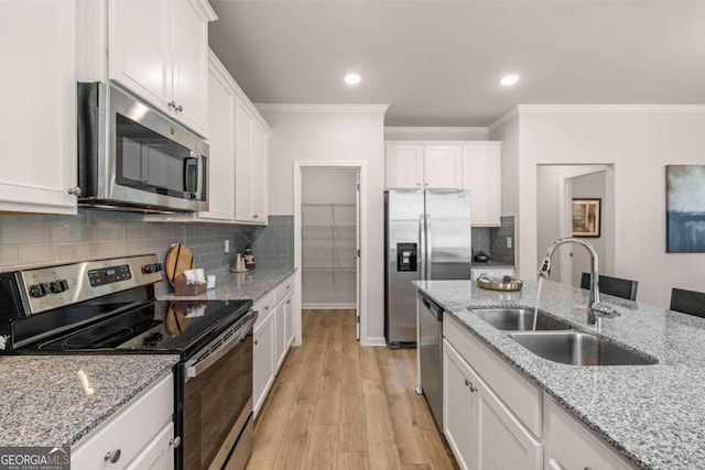 kitchen with appliances with stainless steel finishes, light wood-type flooring, a sink, and white cabinets