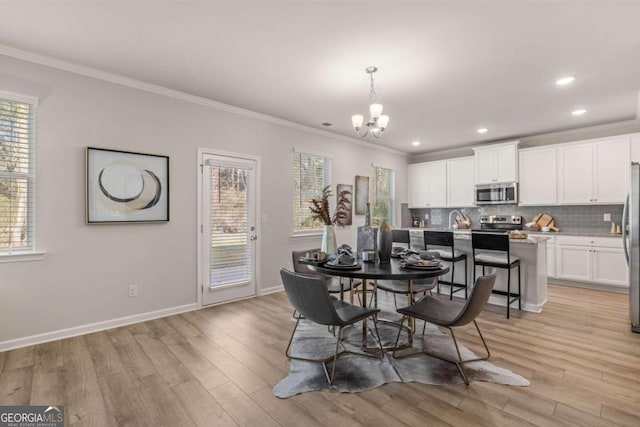 dining room featuring baseboards, light wood finished floors, crown molding, and an inviting chandelier