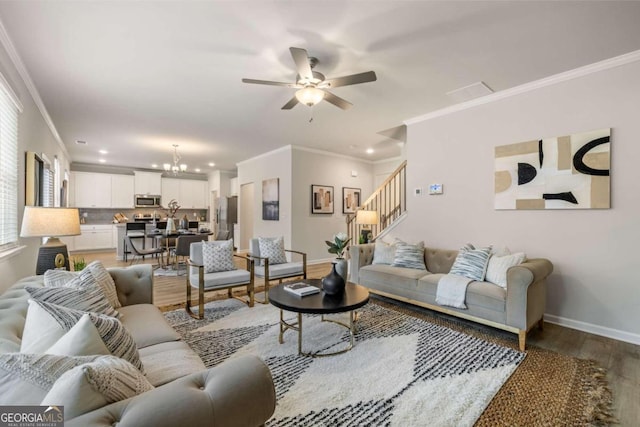 living area featuring light wood finished floors, baseboards, stairs, crown molding, and ceiling fan with notable chandelier