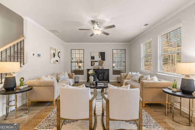 living room with crown molding, visible vents, ceiling fan, and wood finished floors