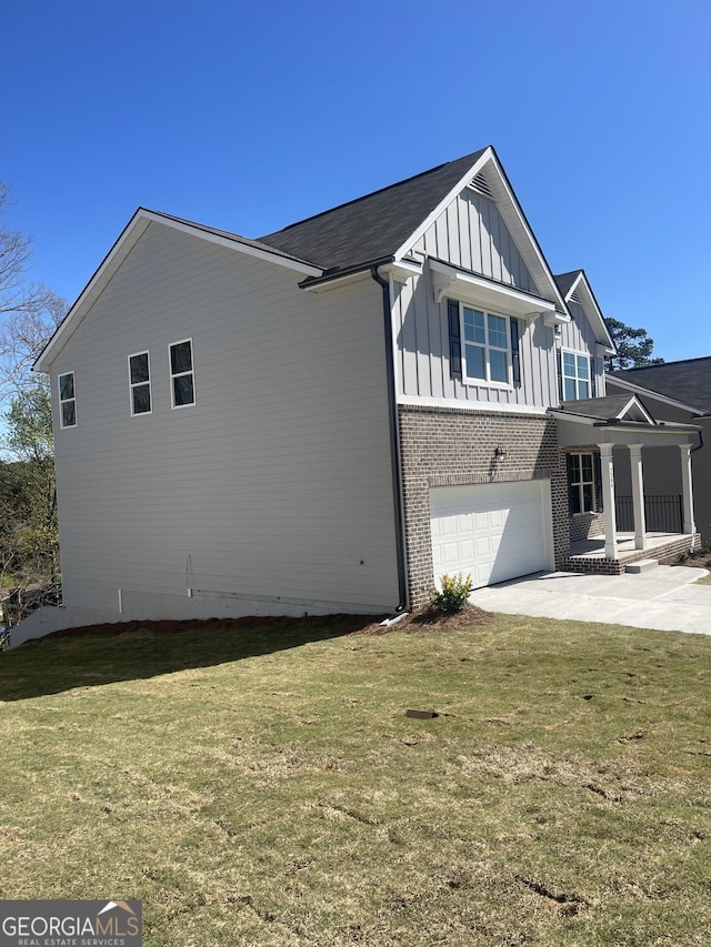 view of side of property with driveway, a garage, a yard, board and batten siding, and brick siding