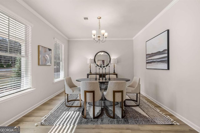 dining room with a notable chandelier, wood finished floors, visible vents, baseboards, and ornamental molding