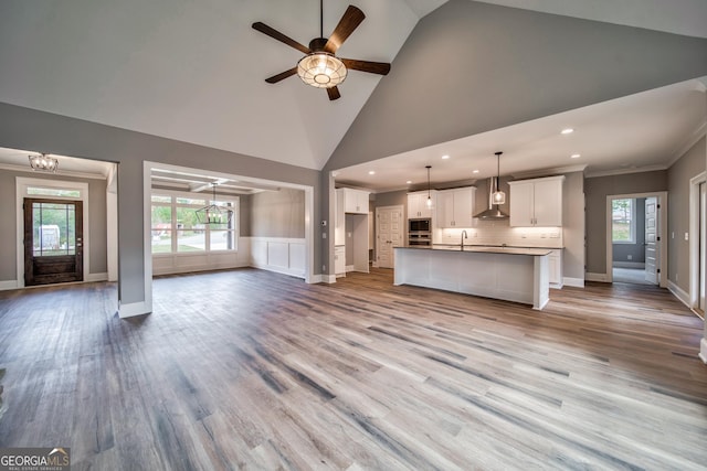 unfurnished living room with wood finished floors, ornamental molding, a healthy amount of sunlight, and a sink