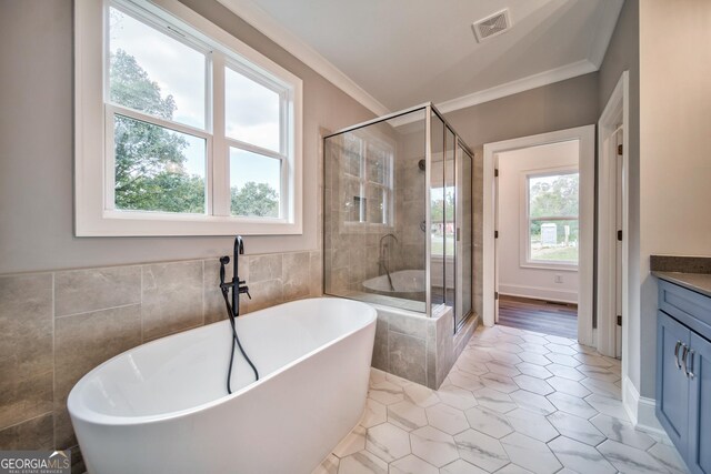 full bathroom featuring vanity, visible vents, a freestanding bath, a shower stall, and crown molding