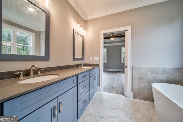 full bath with a wealth of natural light, a freestanding bath, and a sink