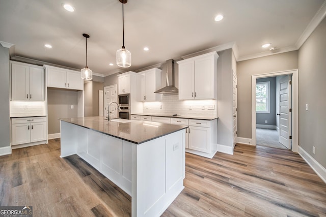 kitchen featuring white cabinetry, appliances with stainless steel finishes, crown molding, and wall chimney range hood