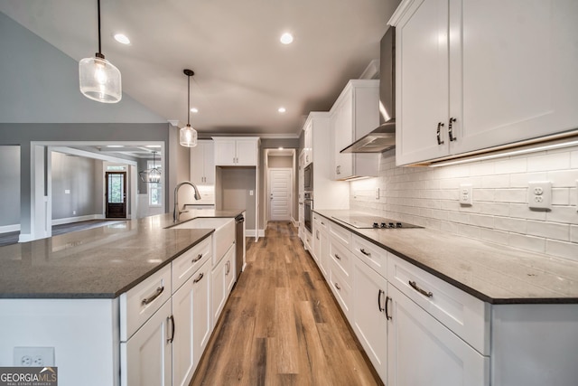 kitchen with a sink, white cabinets, wall chimney exhaust hood, black electric cooktop, and backsplash