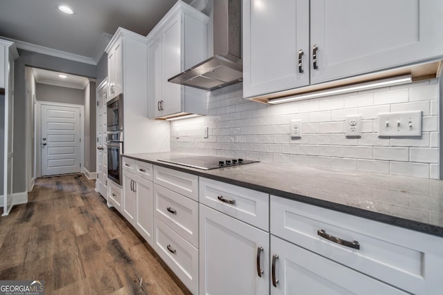 kitchen featuring ornamental molding, appliances with stainless steel finishes, white cabinetry, wall chimney range hood, and tasteful backsplash