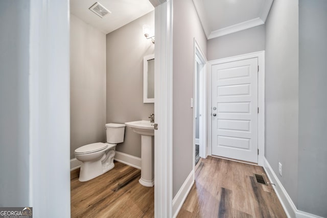 half bath featuring wood finished floors, toilet, baseboards, and visible vents