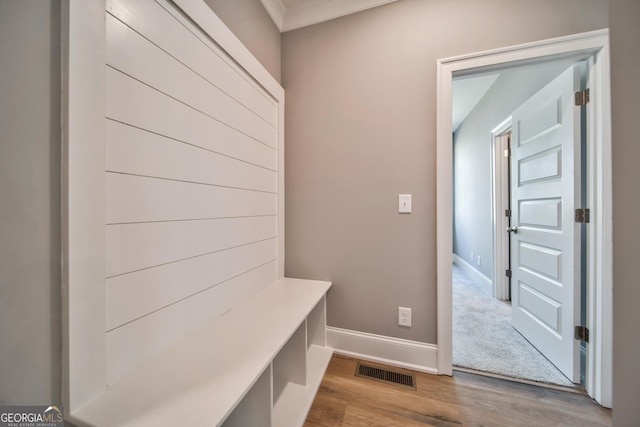 mudroom with crown molding, wood finished floors, visible vents, and baseboards