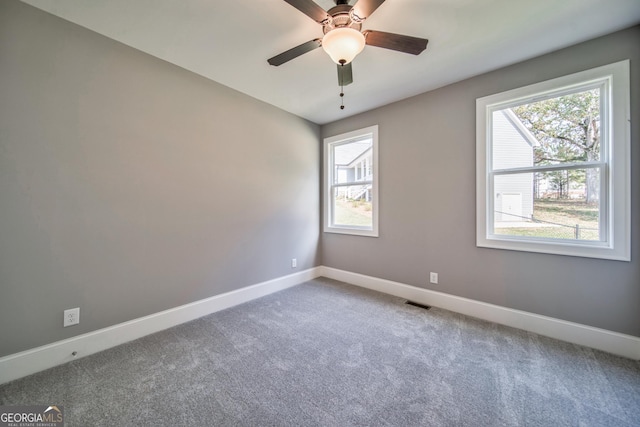 carpeted spare room with visible vents, a ceiling fan, and baseboards