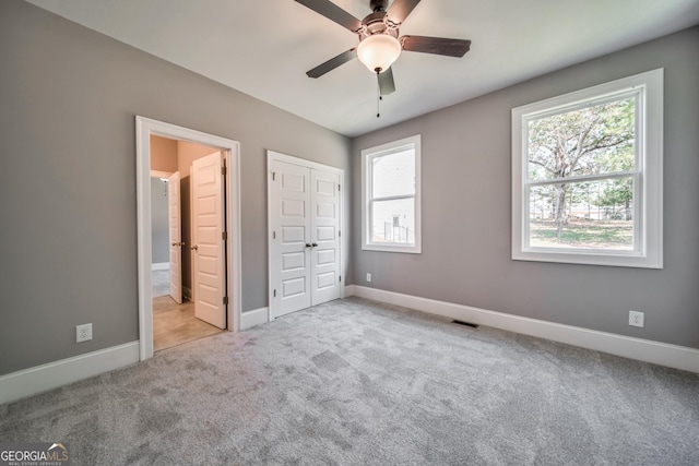 unfurnished bedroom with visible vents, multiple windows, baseboards, and carpet floors