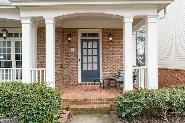 entrance to property with a porch and brick siding