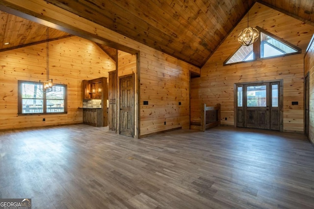 unfurnished living room featuring wood walls, wood ceiling, dark wood-type flooring, and a notable chandelier