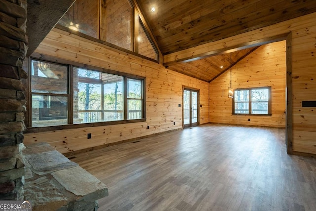 unfurnished living room featuring a healthy amount of sunlight, wood walls, wooden ceiling, and wood finished floors