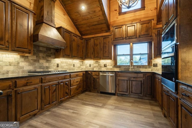 kitchen featuring lofted ceiling, stainless steel appliances, premium range hood, a sink, and light wood-type flooring