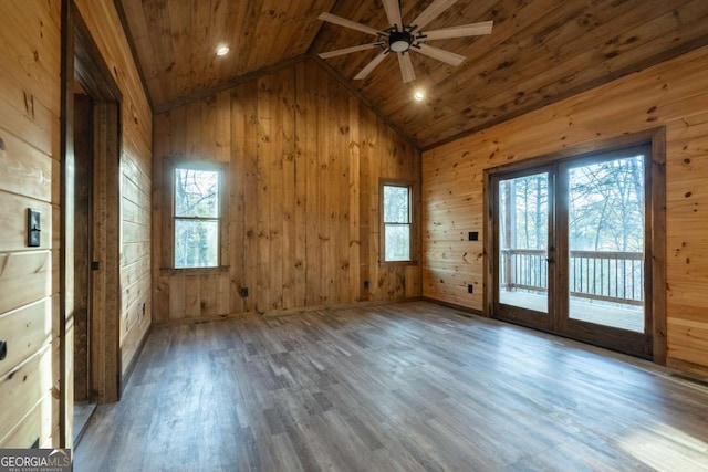 empty room featuring vaulted ceiling, a healthy amount of sunlight, wooden ceiling, and wooden walls