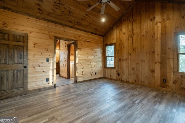 spare room featuring high vaulted ceiling, wooden walls, and wood finished floors