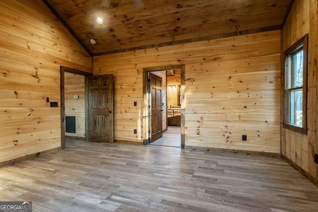 unfurnished room featuring lofted ceiling, wooden ceiling, wooden walls, and wood finished floors