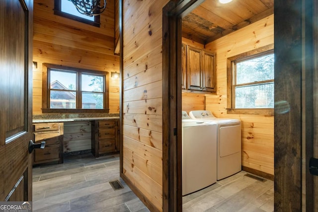 washroom featuring wood walls, washer and clothes dryer, cabinet space, and light wood-style floors