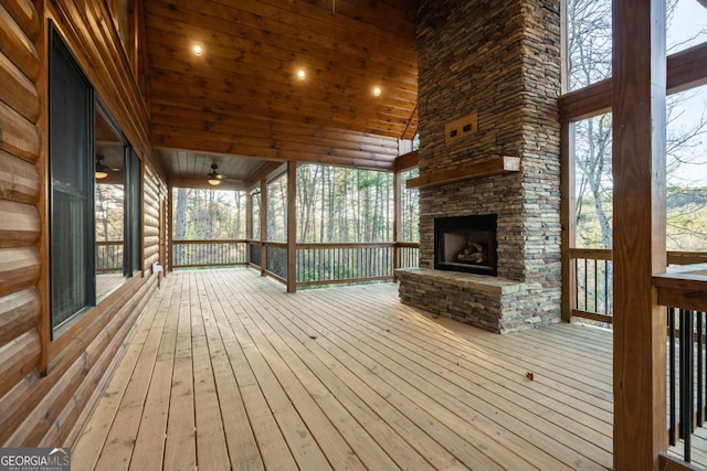 wooden terrace with an outdoor stone fireplace